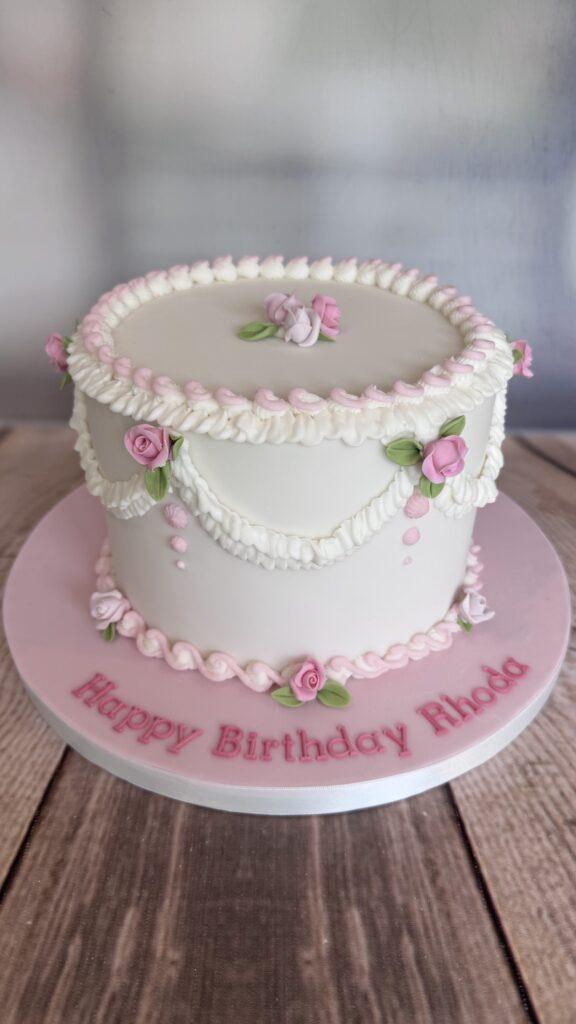 Pretty pink and white vintage Lambeth style birthday cake. Decorated with handmade roses.